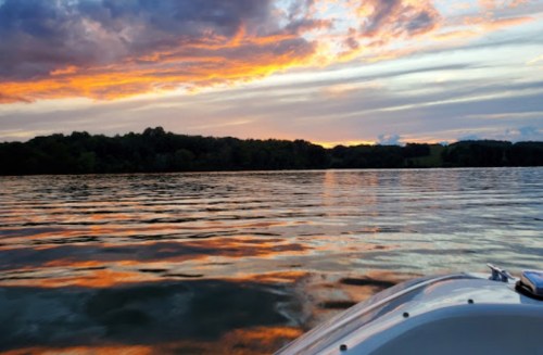 A serene lake at sunset, with vibrant colors reflecting on the water and a boat in the foreground.