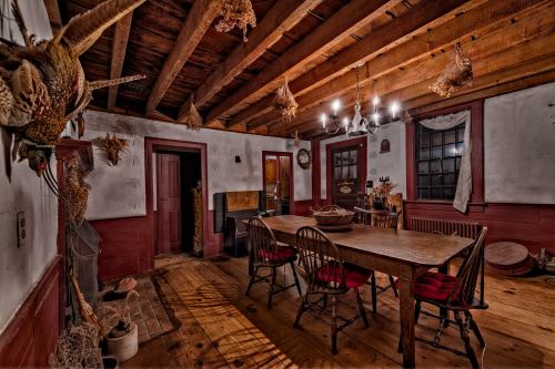 A rustic dining room with a wooden table, chairs, and exposed beams, featuring vintage decor and warm lighting.