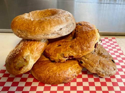 A stack of assorted bagels on a red and white checkered paper.