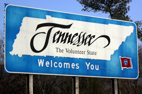 Welcome sign for Tennessee, featuring the state outline and flag, with the text "Tennessee The Volunteer State."