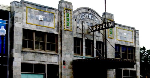 Historic Orpheum theater building with a marquee sign, featuring stone architecture and decorative elements.