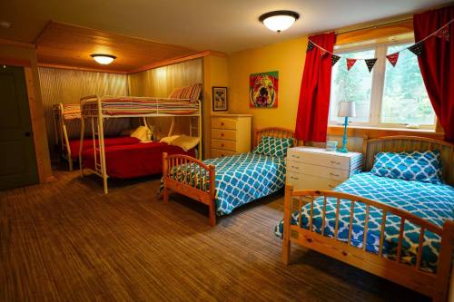 A cozy bedroom with two bunk beds and a single bed, colorful bedding, and bright yellow walls.