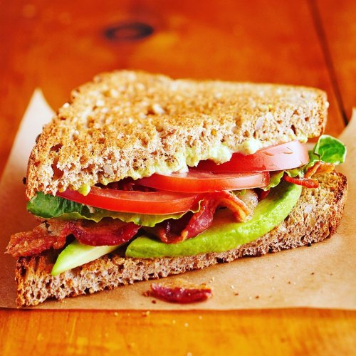A delicious sandwich with layers of bacon, lettuce, tomato, and green apple, served on whole grain bread.