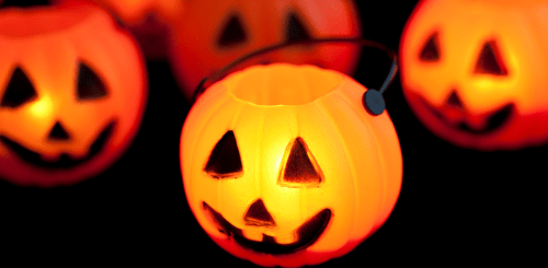 Glowing orange Halloween pumpkin lanterns with smiling faces against a dark background.