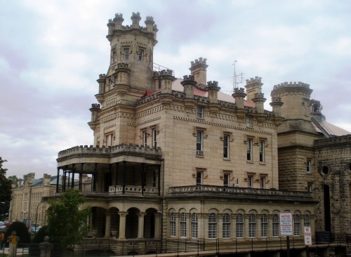 Historic stone building with towers and balconies, featuring intricate architectural details against a cloudy sky.