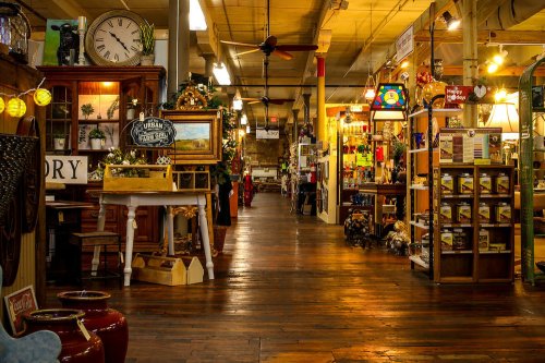 A spacious antique shop with wooden floors, showcasing various vintage items and decor along the aisles.