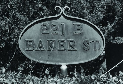 A vintage sign reading "221 B Baker St" surrounded by greenery.