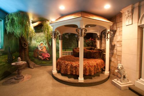 A cozy, circular bed in a gazebo-style setting, surrounded by a mural of nature and decorative sculptures.