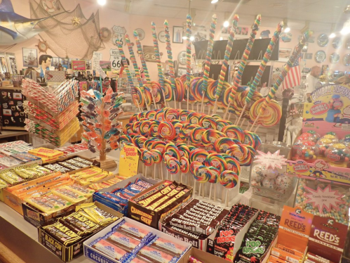 A colorful display of various candies, including lollipops, candy sticks, and boxes of sweets in a shop.