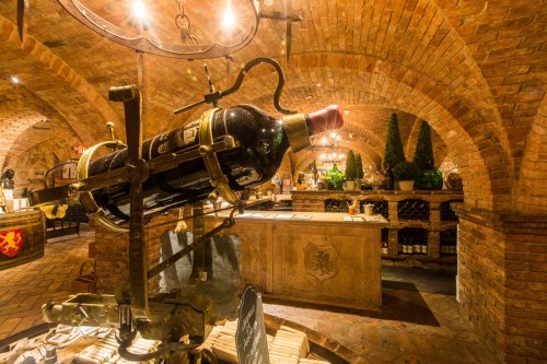 A wine cellar with brick arches, featuring a large wine bottle display and elegant decor.