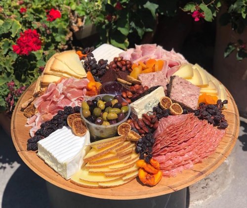 A beautifully arranged charcuterie board with various cheeses, meats, nuts, dried fruits, and olives.