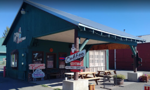 A quaint coffee shop with a blue exterior, outdoor seating, and a sign that reads "Coffee Station."