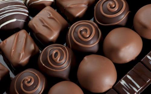 An assortment of various chocolate confections, featuring smooth, glossy finishes and decorative swirls.