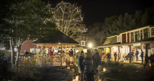 A festive night scene with people enjoying holiday lights and decorations in a charming outdoor setting.