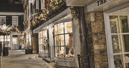 Charming street scene at night, featuring festive holiday decorations and warmly lit shop windows.