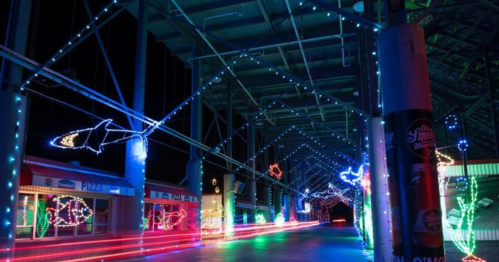 Colorful holiday lights illuminate a covered walkway, featuring fish and ocean-themed decorations.