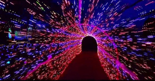A vibrant tunnel of colorful lights creating a dynamic, swirling effect, leading into darkness.