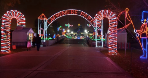 Colorful holiday lights decorate the entrance to Lafreniere Park, with a festive atmosphere and a Christmas tree in the background.
