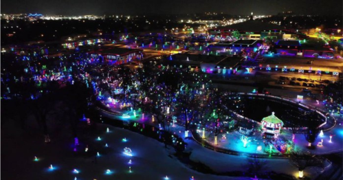 Aerial view of a vibrant holiday light display in a park, featuring colorful lights and decorations at night.