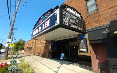 The Cedar Lee Theater marquee displays movie titles, with a brick building and street view in the background.