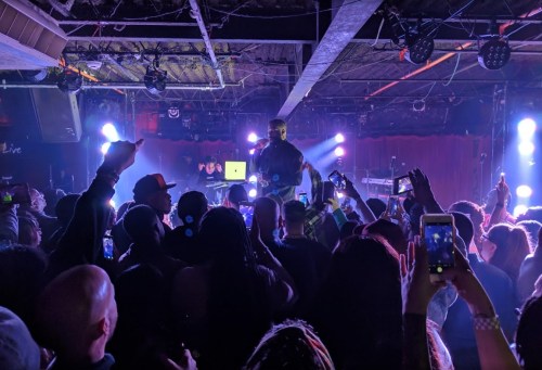 A lively concert scene with a crowd enjoying a performance under colorful stage lights.
