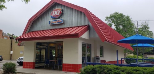 A Dairy Queen restaurant with a red roof and outdoor seating under a blue umbrella.
