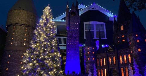 A festive display featuring a large illuminated Christmas tree and a castle-like structure with blue lights.