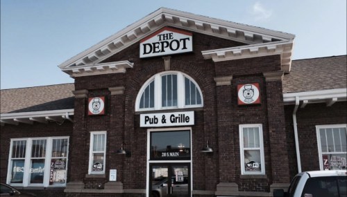 Exterior of The Depot Pub & Grille, featuring a brick facade and large windows, with a sign above the entrance.
