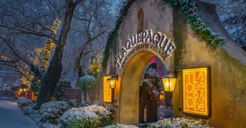 A snowy entrance to La Quippaquque Arts and Crafts Village, adorned with festive lights and greenery.