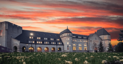 Historic building at sunset, featuring a mix of architectural styles and a vibrant sky with clouds.