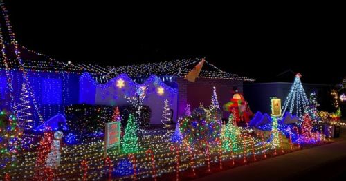 A festive display of colorful Christmas lights adorning houses and trees, creating a cheerful holiday atmosphere at night.