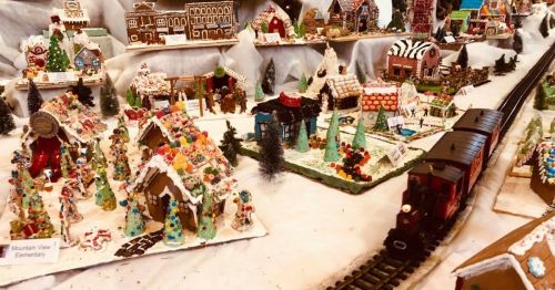 A festive display of gingerbread houses and decorations with a toy train running through a snowy landscape.