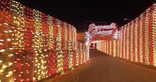 A festive entrance adorned with red and white lights, featuring a sign that reads "Peppermint Parkway."