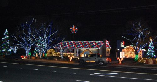 A house decorated with colorful Christmas lights, featuring trees, candy canes, and a festive star in the night sky.