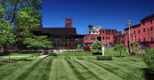 A vibrant green lawn in front of a historic red brick building under a clear blue sky.