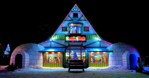 A brightly lit, festive building resembling a toy shop, with igloo-shaped structures and holiday decorations at night.