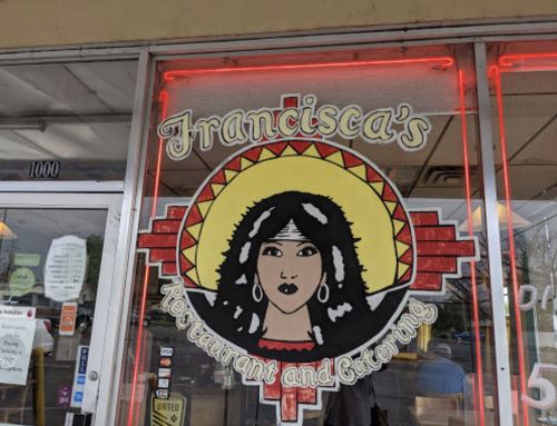 Sign for "Francisca's Restaurant and Catering" featuring a stylized woman with a sunburst design in the background.