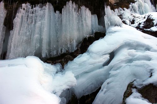 Icicles and frozen ice formations create a stunning winter landscape, with layers of white and blue ice.