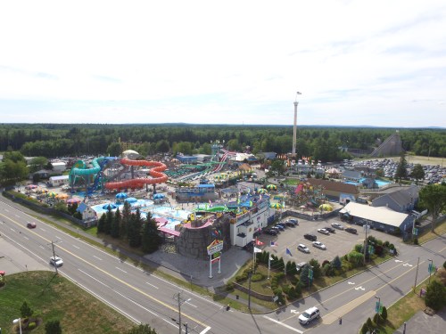 Aerial view of a vibrant water park with slides, pools, and attractions, surrounded by greenery and a parking lot.