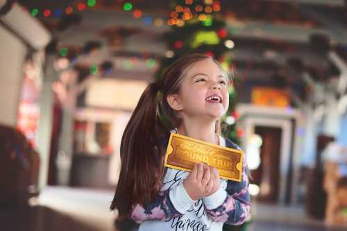 A joyful girl holds a round-trip ticket, smiling in a festive, decorated setting with colorful lights.