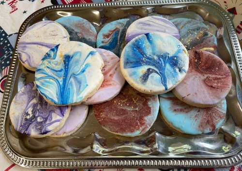 A silver tray filled with colorful, marbled cookies in various shades of blue, purple, and brown.