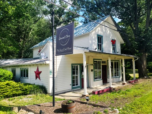 A charming white house with a blue roof, featuring a sign for a store and red star decorations on the exterior.