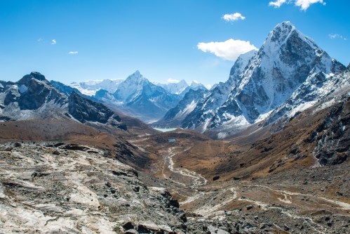A breathtaking mountain landscape with snow-capped peaks and a winding valley under a clear blue sky.