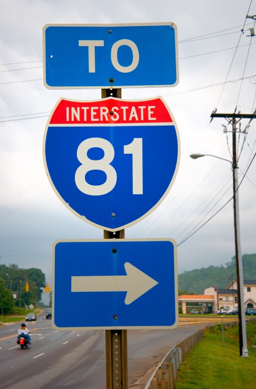 Sign directing traffic to Interstate 81, featuring a blue background with a red shield and an arrow pointing right.
