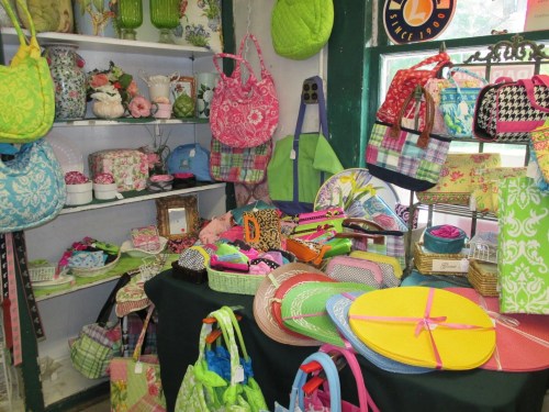 A colorful display of bags, hats, and accessories on shelves and tables in a charming shop.