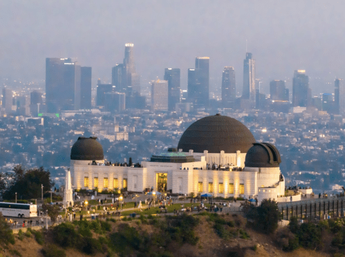 The Griffith Observatory illuminated at dusk, with the Los Angeles skyline in the background.