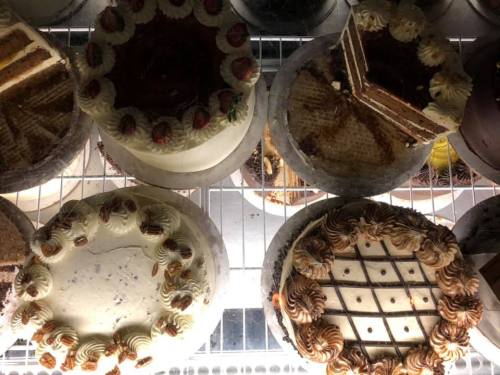 A variety of cakes displayed in a glass case, featuring different flavors and decorations.