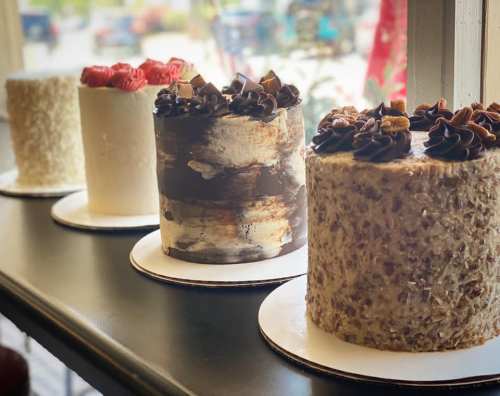 Four beautifully decorated cakes on a table, featuring chocolate, red velvet, and coconut frosting designs.