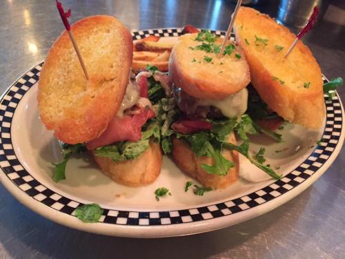Two sandwiches with lettuce, meat, and cheese, served on a plate with fries, garnished with parsley and toothpicks.
