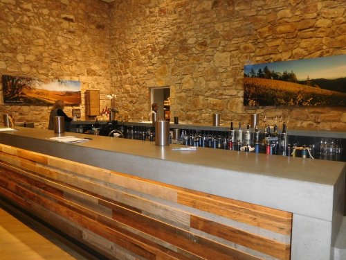 A modern bar with a stone wall backdrop, featuring a sleek countertop and bottles lined up on the shelves.